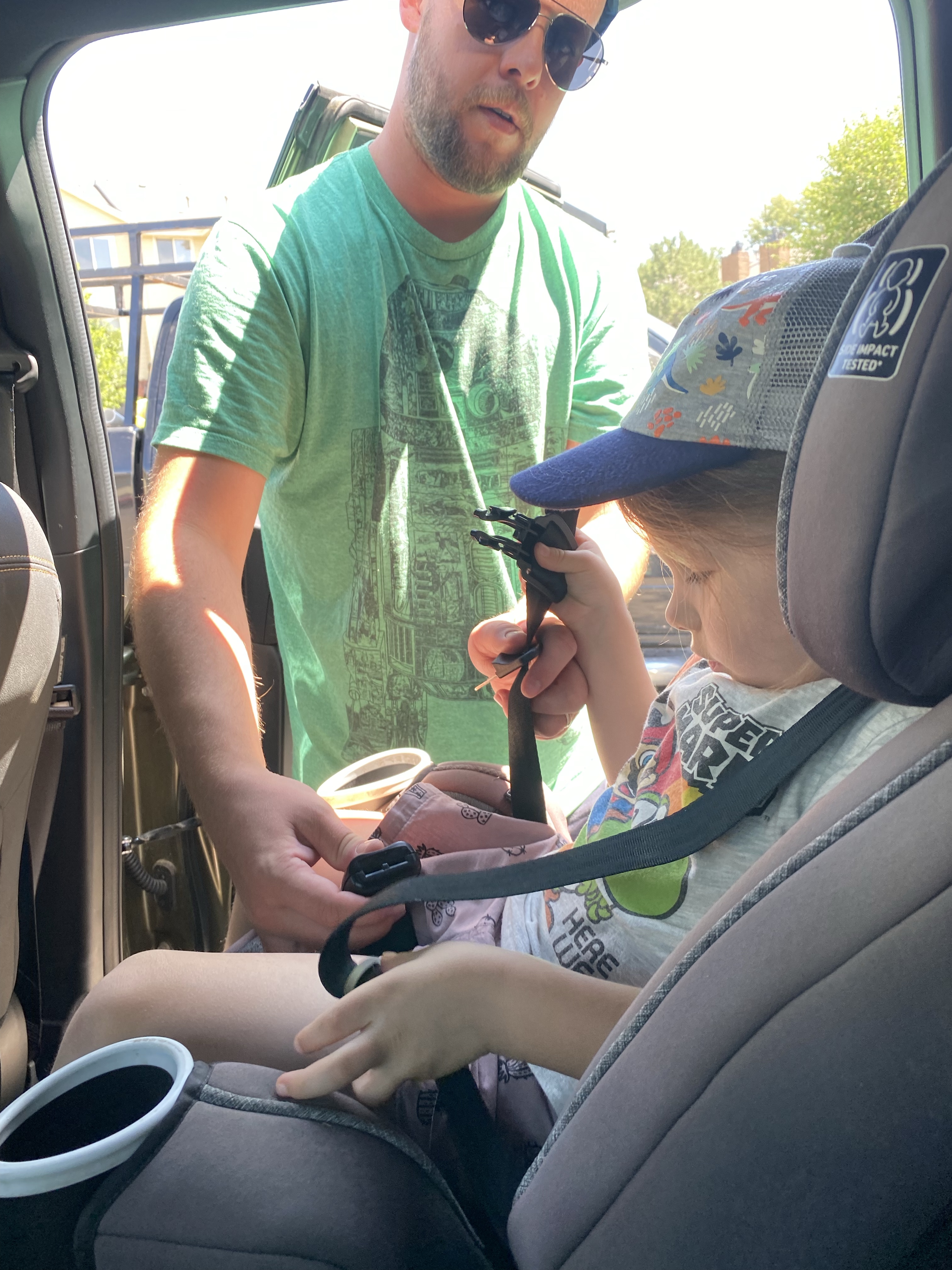 Dad buckles Ben into his car seat.